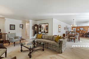 Living room with light colored carpet, an inviting chandelier, and crown molding