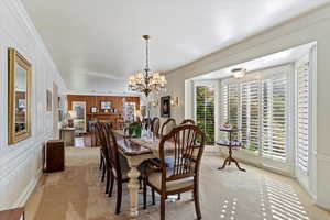 Carpeted dining room with ornamental molding and a chandelier