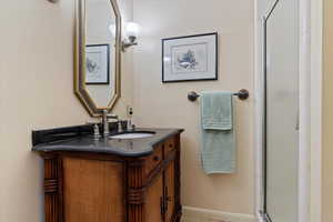 Bathroom featuring a shower with shower door and vanity