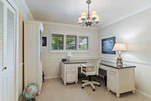 Carpeted office with a notable chandelier and crown molding