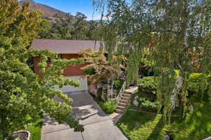 View of property hidden behind natural elements featuring a mountain view and a garage