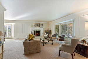 Living room featuring light carpet, crown molding, and a tiled fireplace