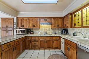 Kitchen featuring stainless steel appliances, decorative backsplash, sink, and tile counters