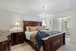 Carpeted bedroom featuring ornamental molding and an inviting chandelier