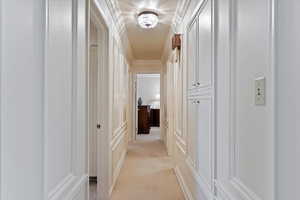 Corridor featuring light colored carpet and crown molding