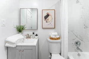 Full bathroom featuring shower / bathtub combination with curtain, vanity, and toilet