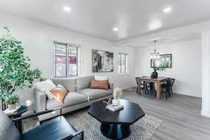 Living room featuring a textured ceiling, light wood-type flooring, a chandelier, and a healthy amount of sunlight