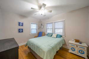 Bedroom with hardwood / wood-style floors, multiple windows, and ceiling fan