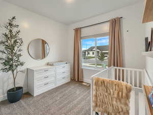 Bedroom with light carpet and a crib