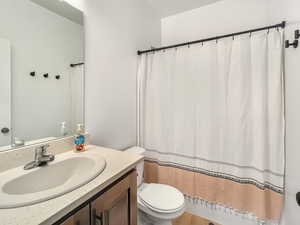 Bathroom featuring hardwood / wood-style flooring, vanity, walk in shower, and toilet