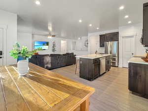 Kitchen featuring ceiling fan, appliances with stainless steel finishes, light wood-type flooring, and a kitchen island with sink