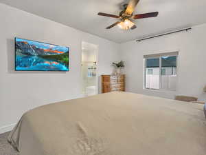 Carpeted bedroom featuring ceiling fan and ensuite bath