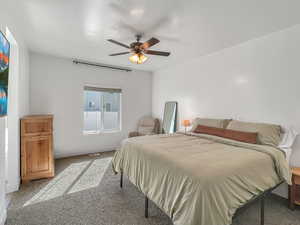 Bedroom with ceiling fan, a textured ceiling, and carpet flooring