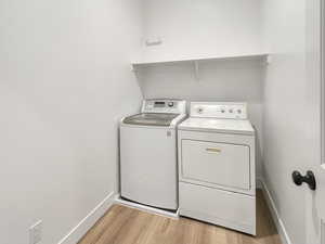 Laundry room with independent washer and dryer and light hardwood / wood-style floors