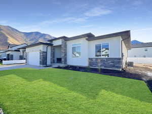 View of front of house featuring a mountain view, a garage, a front lawn, and central AC