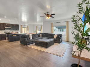 Living room featuring ceiling fan, light hardwood / wood-style flooring, and a textured ceiling