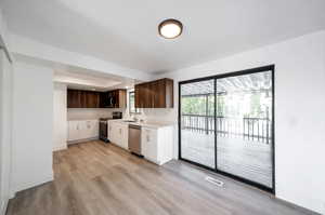 Kitchen with dark brown cabinetry, stainless steel appliances, sink, and light hardwood / wood-style flooring