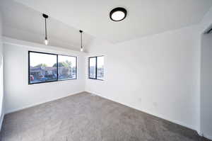 Spare room featuring vaulted ceiling and carpet flooring