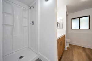 Bathroom with vanity, a shower, hardwood / wood-style floors, and toilet