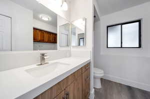 Bathroom with hardwood / wood-style floors, vanity, and toilet