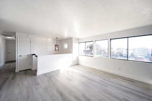 Unfurnished room with hardwood / wood-style floors, a chandelier, and a textured ceiling