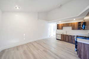 Kitchen featuring stainless steel appliances, sink, lofted ceiling, and light hardwood / wood-style flooring