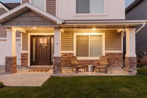 View of exterior entry with a yard and covered porch