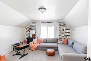 Carpeted living room featuring vaulted ceiling