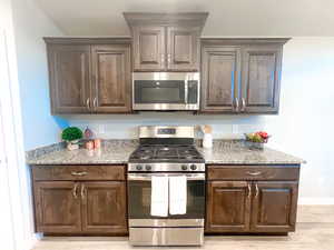 Kitchen featuring stainless steel appliances, light stone counters, and hardwood cabinets