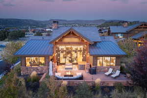 Back house at dusk with a mountain view, a multi sided fireplace, and patio