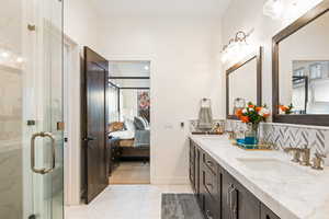 Bathroom with vanity, tile patterned floors, a shower with door, and decorative backsplash