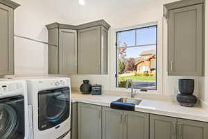 Laundry area with washing machine and clothes dryer, sink, and cabinets