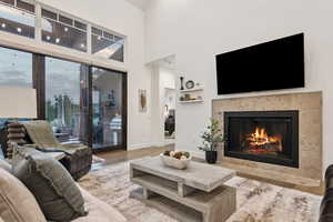 Living room with a towering ceiling, hardwood / wood-style floors, and a tile fireplace