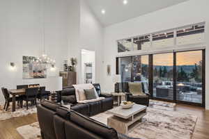 Living room with hardwood / wood-style flooring, a notable chandelier, and high vaulted ceiling