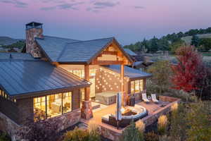 Back house at dusk featuring a jacuzzi and a patio