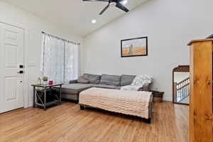 Living room with high vaulted ceiling, ceiling fan, and light hardwood / wood-style flooring