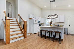 Kitchen with pendant lighting, white cabinets, white appliances, and a center island