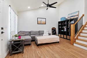 Living room with ceiling fan, hardwood / wood-style flooring, and vaulted ceiling