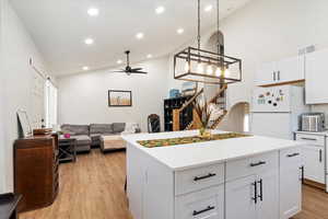 Kitchen with ceiling fan, white cabinets, white refrigerator, a kitchen island, and light hardwood / wood-style flooring