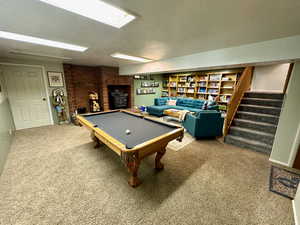 Rec room featuring carpet floors, a textured ceiling, billiards, and a wood stove