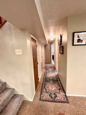 Hall with carpet floors and a textured ceiling