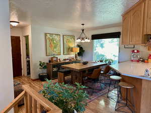 Dining area featuring an inviting chandelier, light hardwood / wood-style flooring, and a textured ceiling