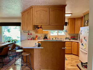 Kitchen with white refrigerator, light hardwood / wood-style flooring, and a healthy amount of sunlight