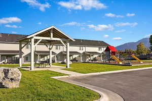 Rear view of house with a playground, a mountain view, and a lawn