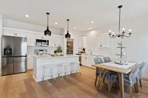 Kitchen featuring white cabinets, stainless steel appliances, a kitchen island, and hanging light fixtures