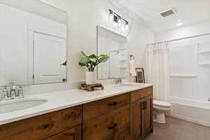 Full bathroom with tile patterned floors, vanity, toilet, and shower / bath combo with shower curtain