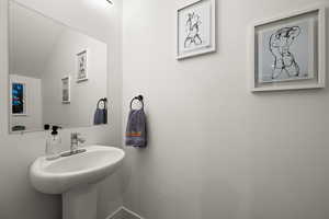 Bathroom with vaulted ceiling, a textured ceiling, and sink