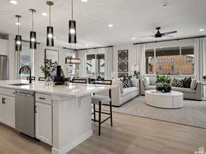 Kitchen featuring an island with sink, pendant lighting, a healthy amount of sunlight, and white cabinetry