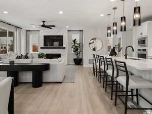 Living room with light hardwood / wood-style flooring, a high end fireplace, sink, and ceiling fan