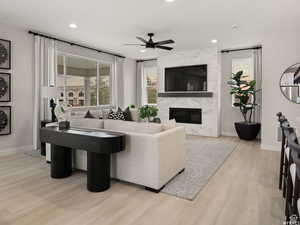 Living room featuring a fireplace, ceiling fan, and light hardwood / wood-style floors